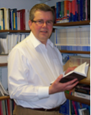 Professor Kevin Featherstone Head of the European Institute holding a book in the library