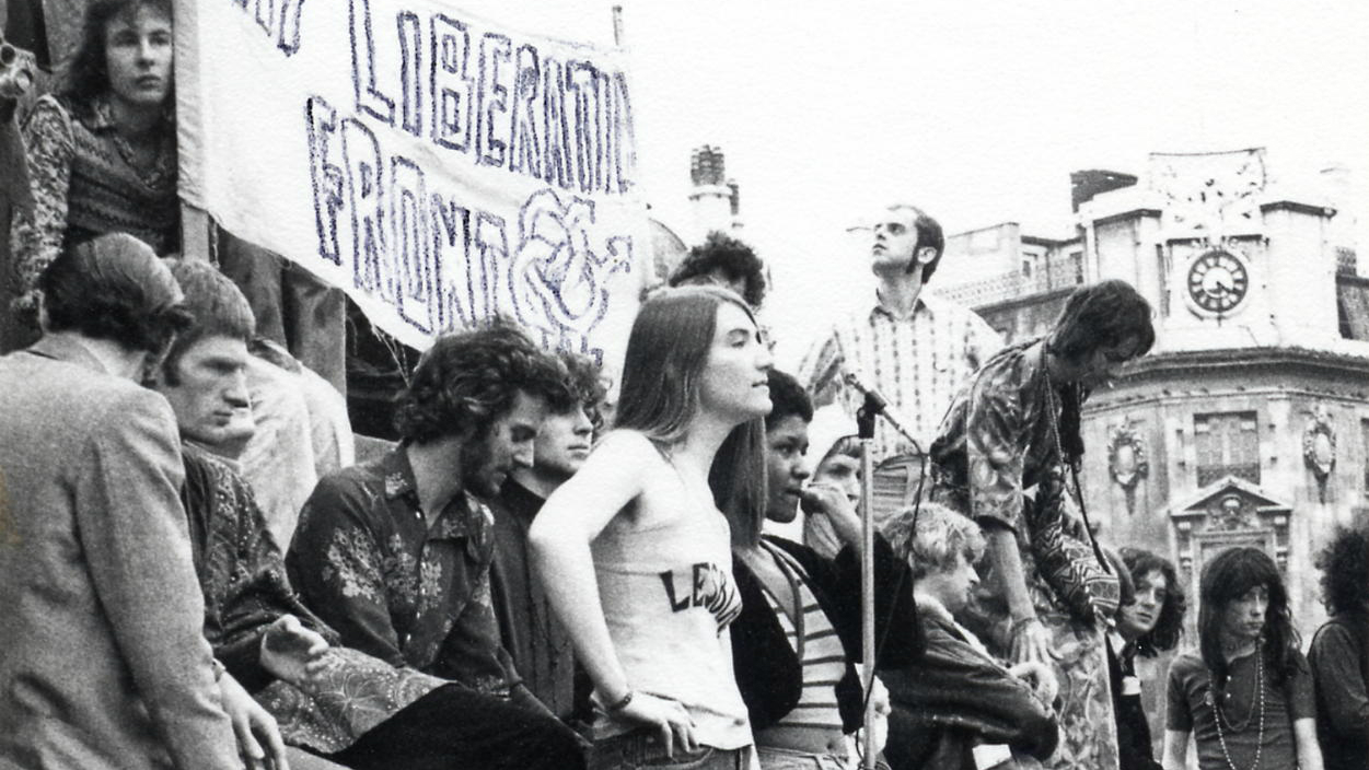 A 1972 demonstration, with people gathered around a Gay Liberation Front banner