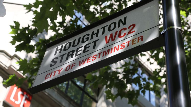 A sign saying Houghton Street beneath trees on a sunny day