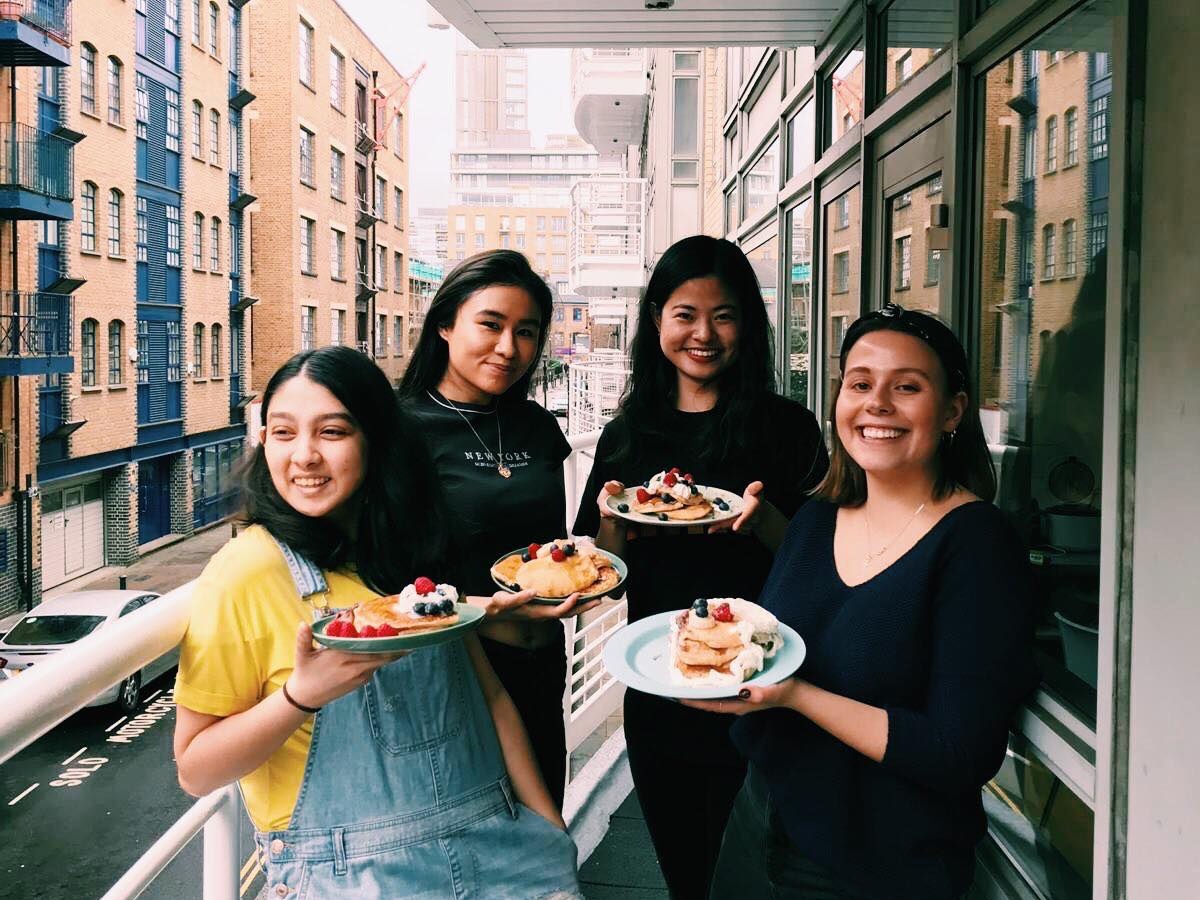 LSE social media ambassadors standing on a balcony with their plates of homemade vegan banana pancakes