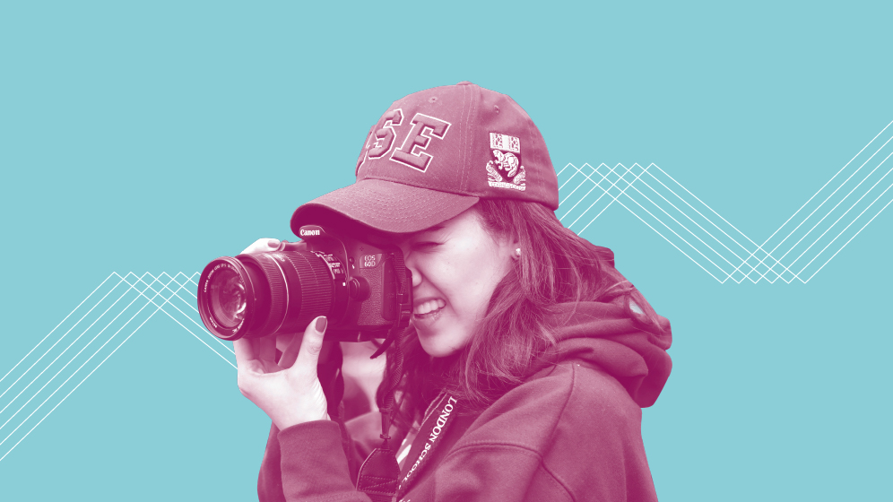 A woman taking a photo with a camera with a light blue background