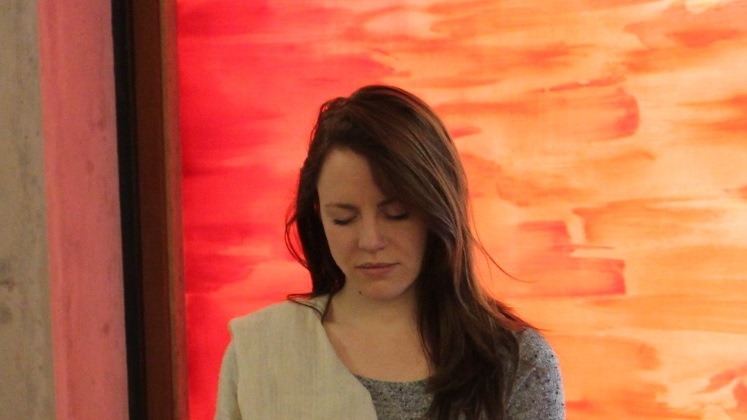 Woman in deep meditation with light orange faith centre desert room window in the background