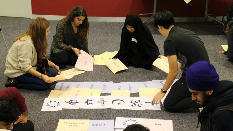 Interfaith Buddies welcome week activity with a multifaith group sitting on the floor in dialogue.