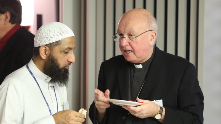 Priest and Imam in discussion over food.