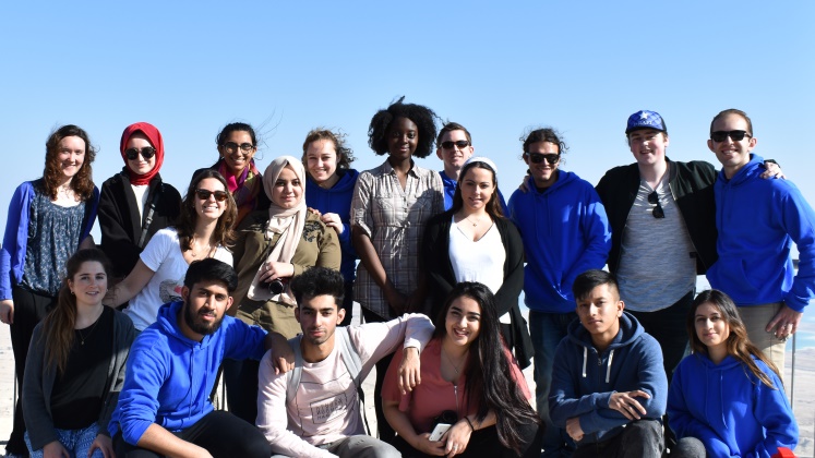 LSE Interfaith Encounter group of 20 students in blue hoodies in bright blue sky.