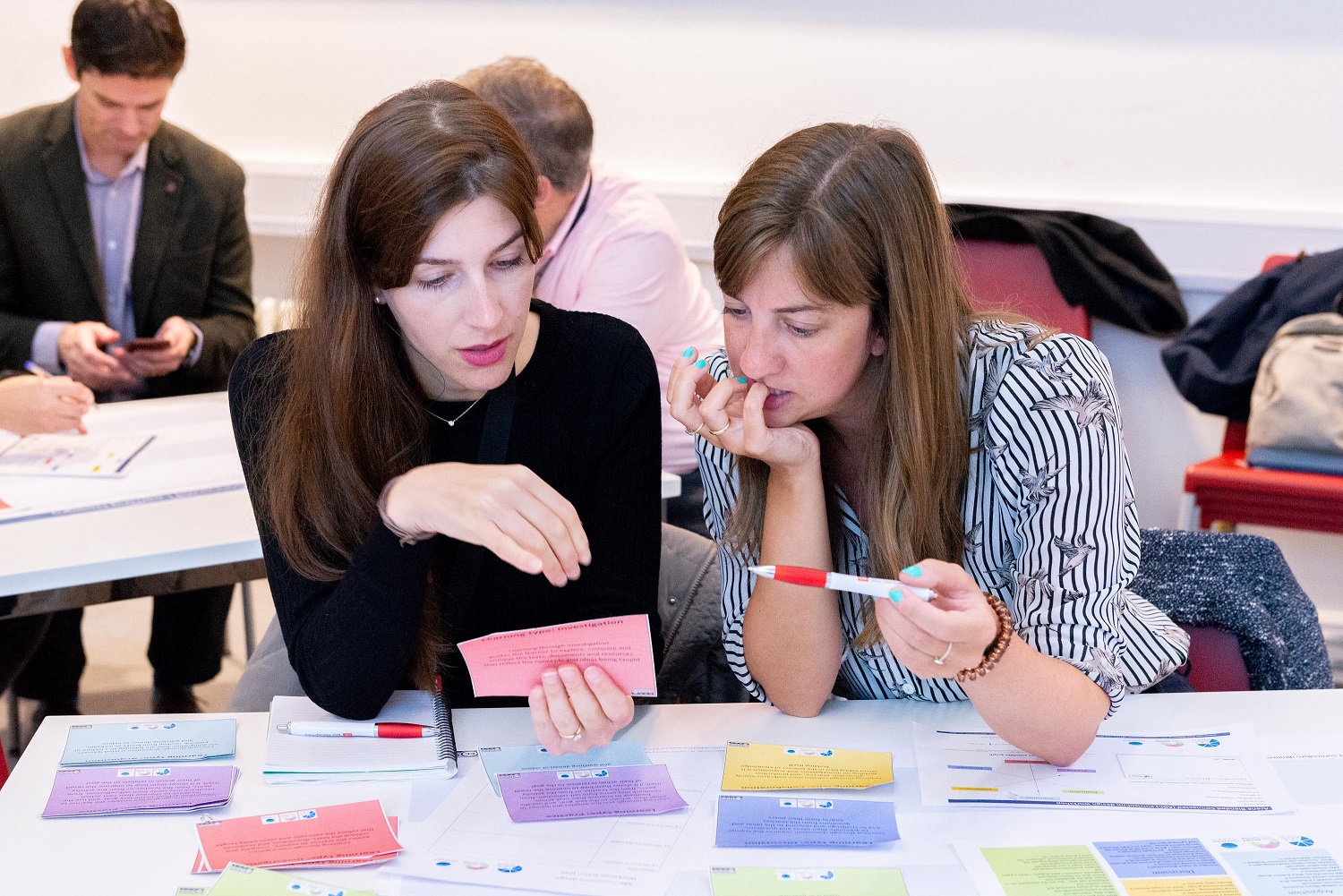 two colleagues discussing ideas at a table covering in post-it notes