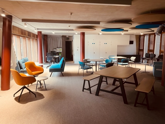 The inside of the Community Space, showing a spacious room with comfortable colourful furniture and gentle spotlight lighting