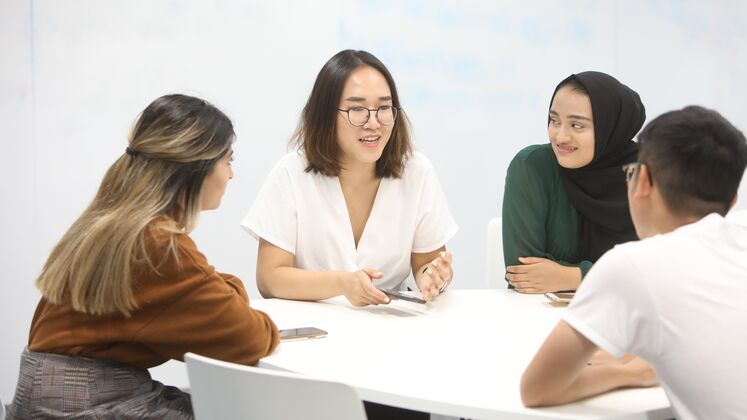 Photo of students around a table talking