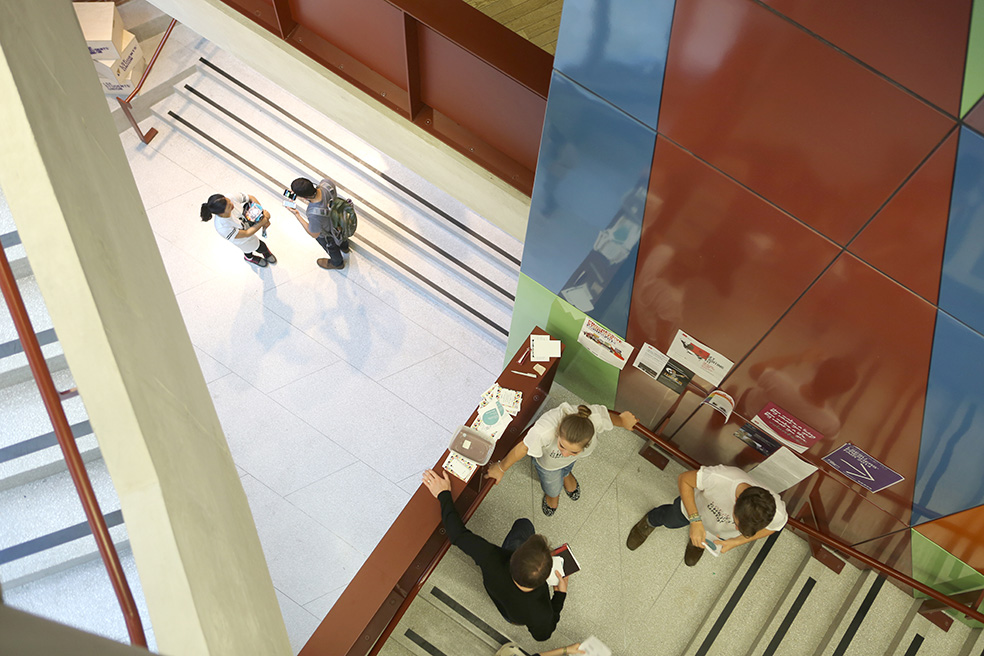 A view from above of three people talking on a staircase