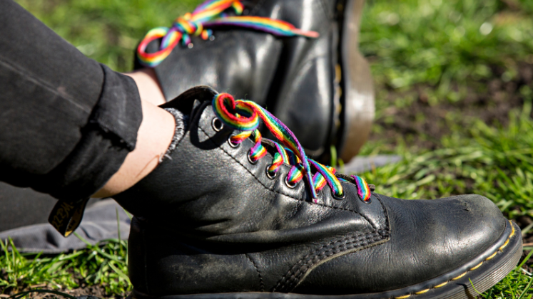 A pair of black boots with pride laces